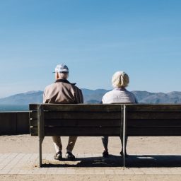 An older couple sitting together on a bench.